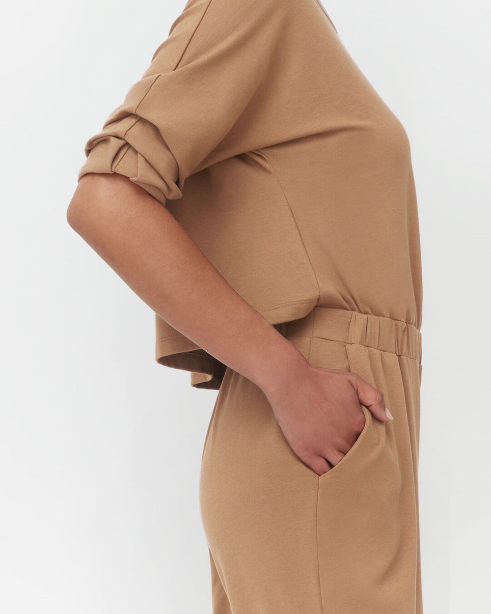 Person standing with hand in pocket, cropped view from mid-torso to thighs.