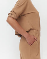 Person standing with hand in pocket, cropped view from mid-torso to thighs.