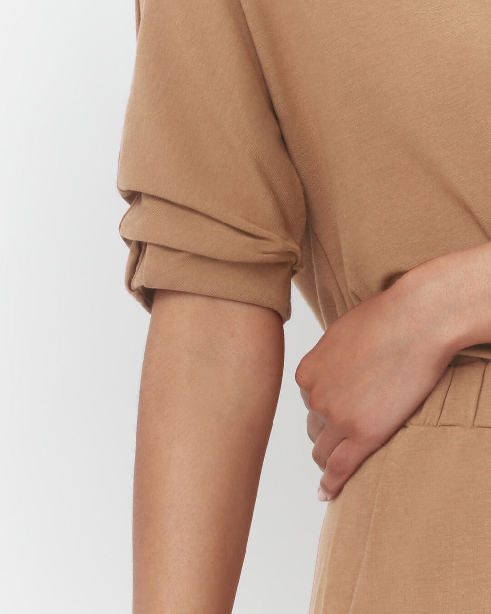 Person standing with hand on hip, showing arm and torso.