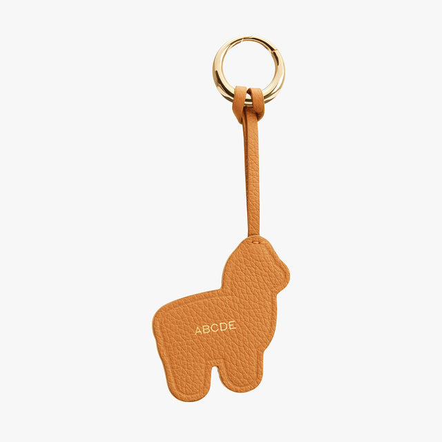 Keychain shaped like an alpacawith letters on it and attached to a ring.