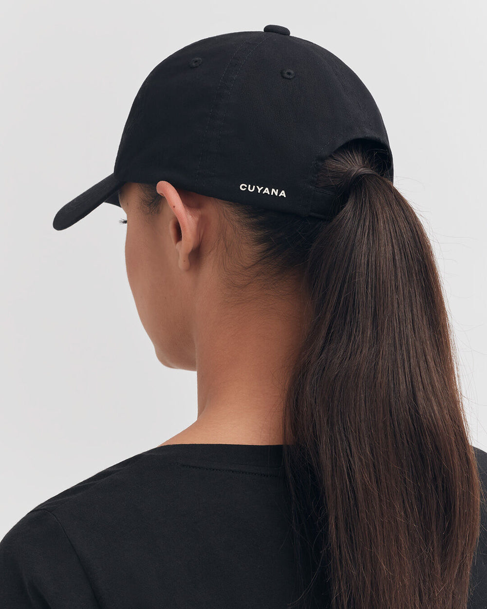 Woman wearing a baseball cap with ponytail through the back.