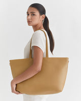 Woman holding a large tote bag over her shoulder, looking over her shoulder.