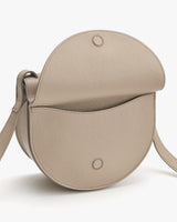 Round leather shoulder bag with a flap.