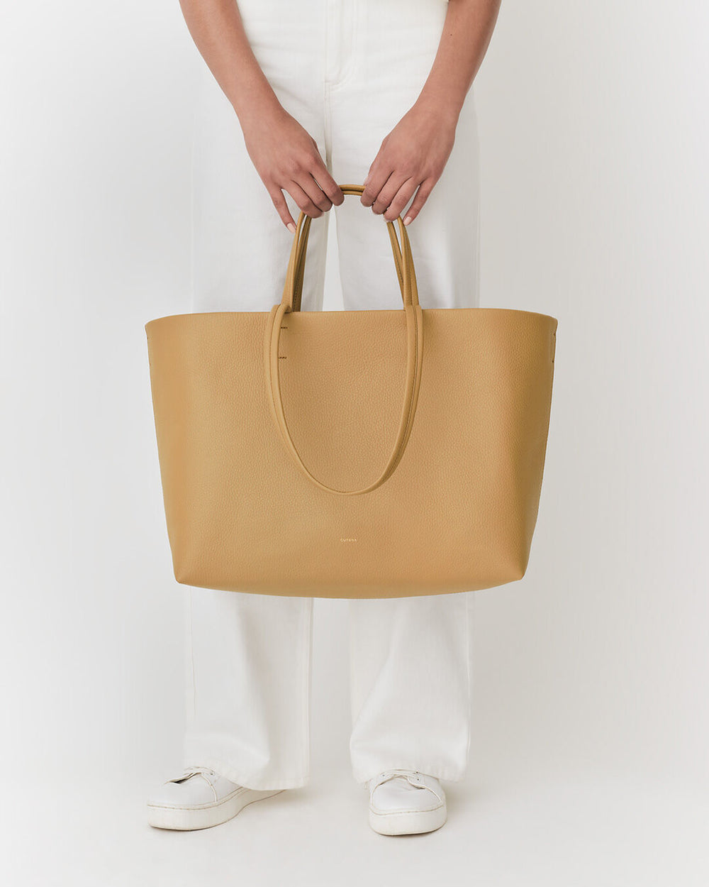 Person standing and holding a large handbag.