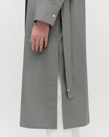 Close-up of a person wearing a long coat with hand visible.