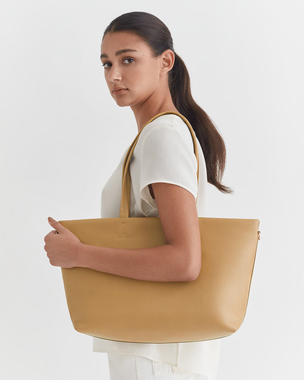 Woman holding a large bag, looking over her shoulder.