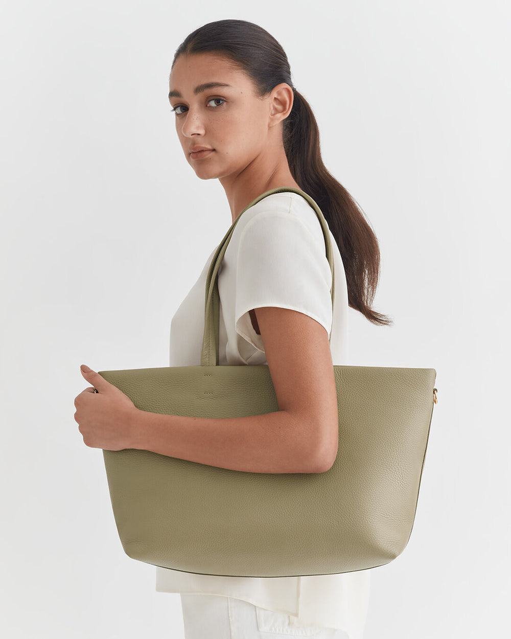 Woman holding a large tote bag, looking over her shoulder.