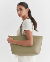 Woman holding a large tote bag, looking over her shoulder.