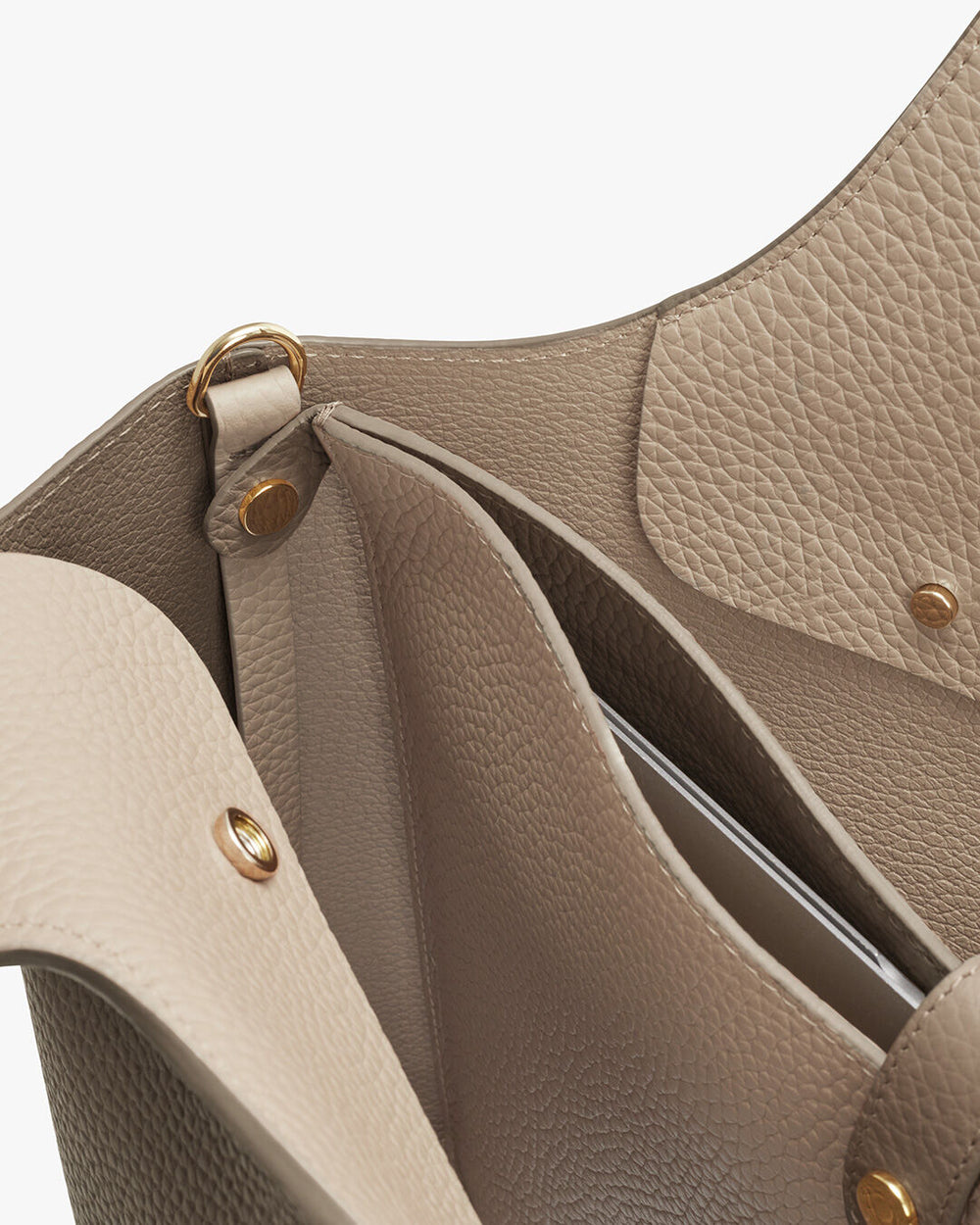 Close-up of an open handbag showing the interior and snap fasteners.