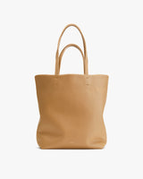 Leather tote bag with two handles, standing upright.