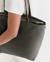 Person holding a large handbag with a zipper detail.