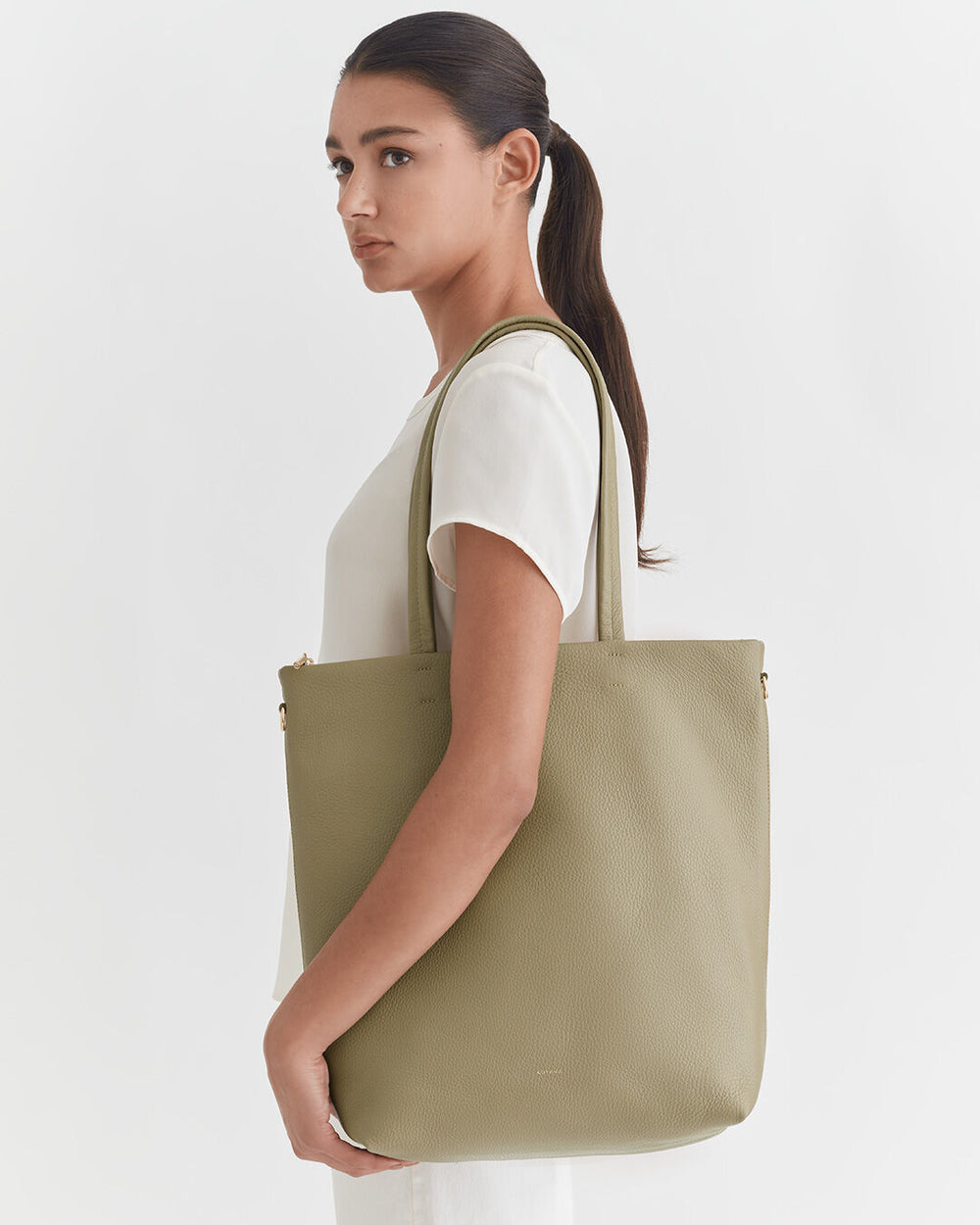 Woman carrying a shoulder bag, facing sideways.
