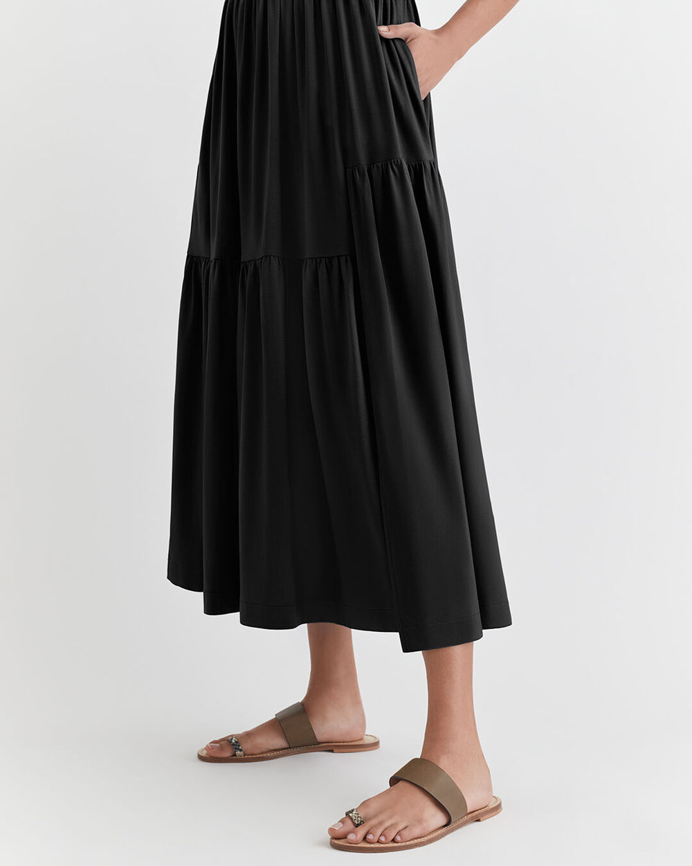 Person wearing a tiered long skirt and flat sandals, partial view.