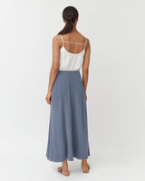 Woman in a sleeveless top and flowing skirt, viewed from back.