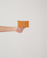 Hand holding a small wallet with a zipper.