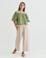 Woman standing in off-shoulder top and wide-leg pants