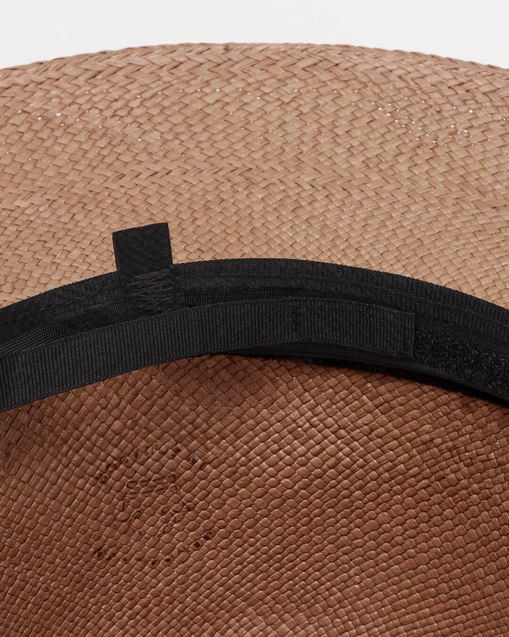 Close-up of a woven hat with a band around it.