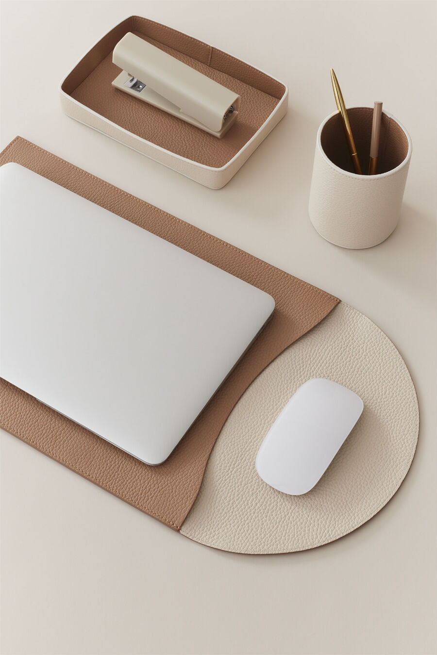 Laptop, mouse on oval mat, and stationery holder on desk tray.