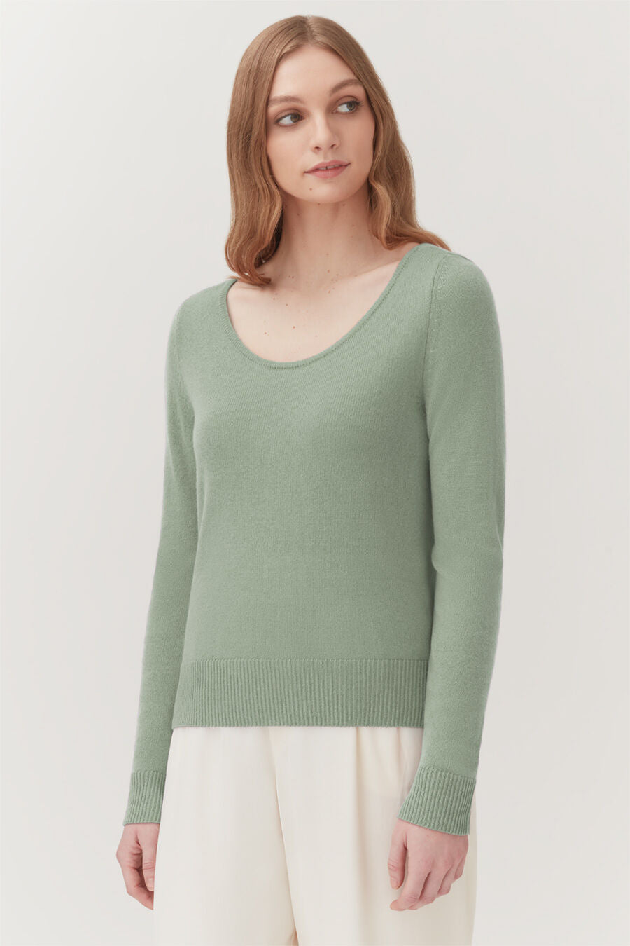 Woman in a sweater standing, looking to her right.
