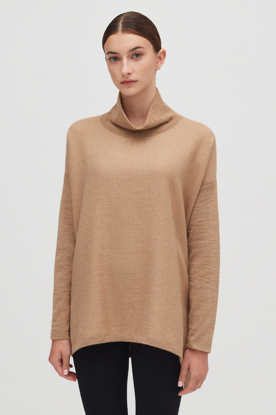 Woman wearing a turtleneck sweater standing straight with a neutral expression.