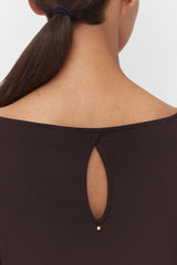 Woman wearing a top with a back keyhole detail and ponytail.