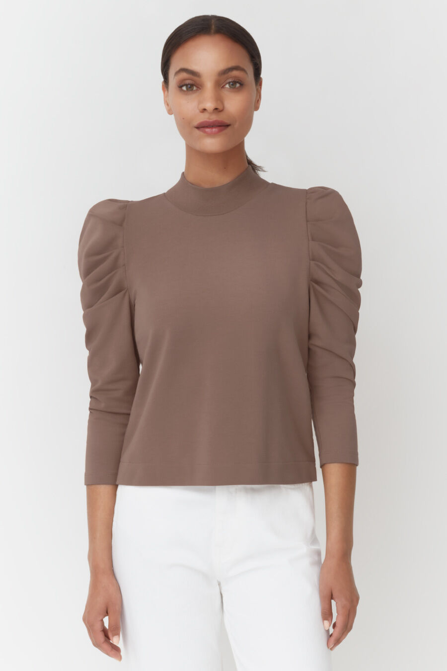 Woman standing with hands at her sides wearing a top with puffy sleeves.