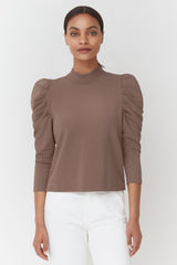 Woman standing with hands at her sides wearing a top with puffy sleeves.