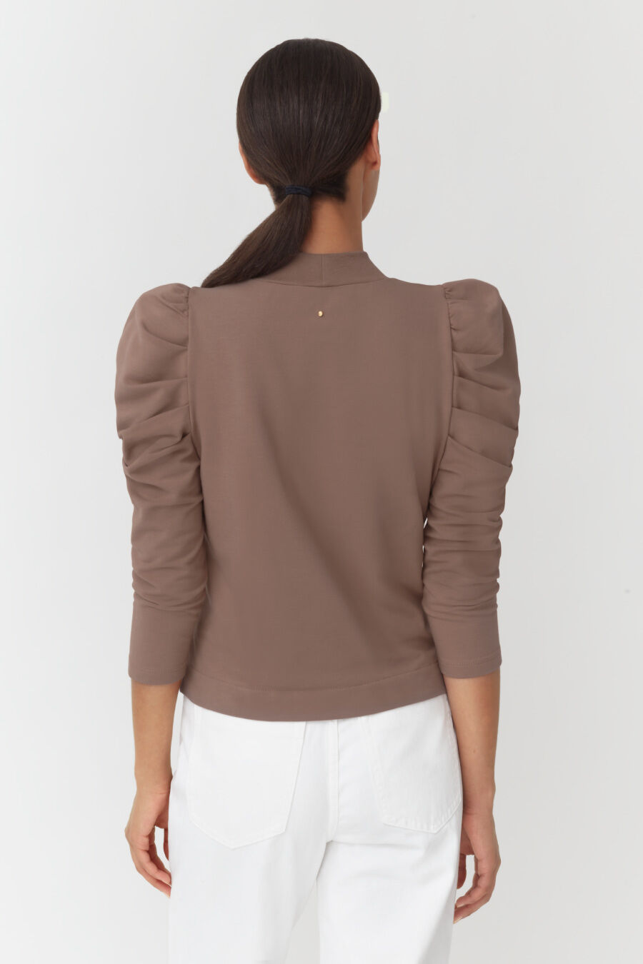 Woman facing away with a ponytail, wearing a top with puffed sleeves.