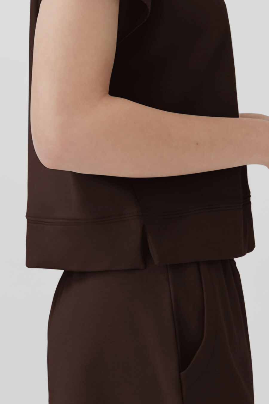 Person in a sleeveless top and matching pants seen from the side.