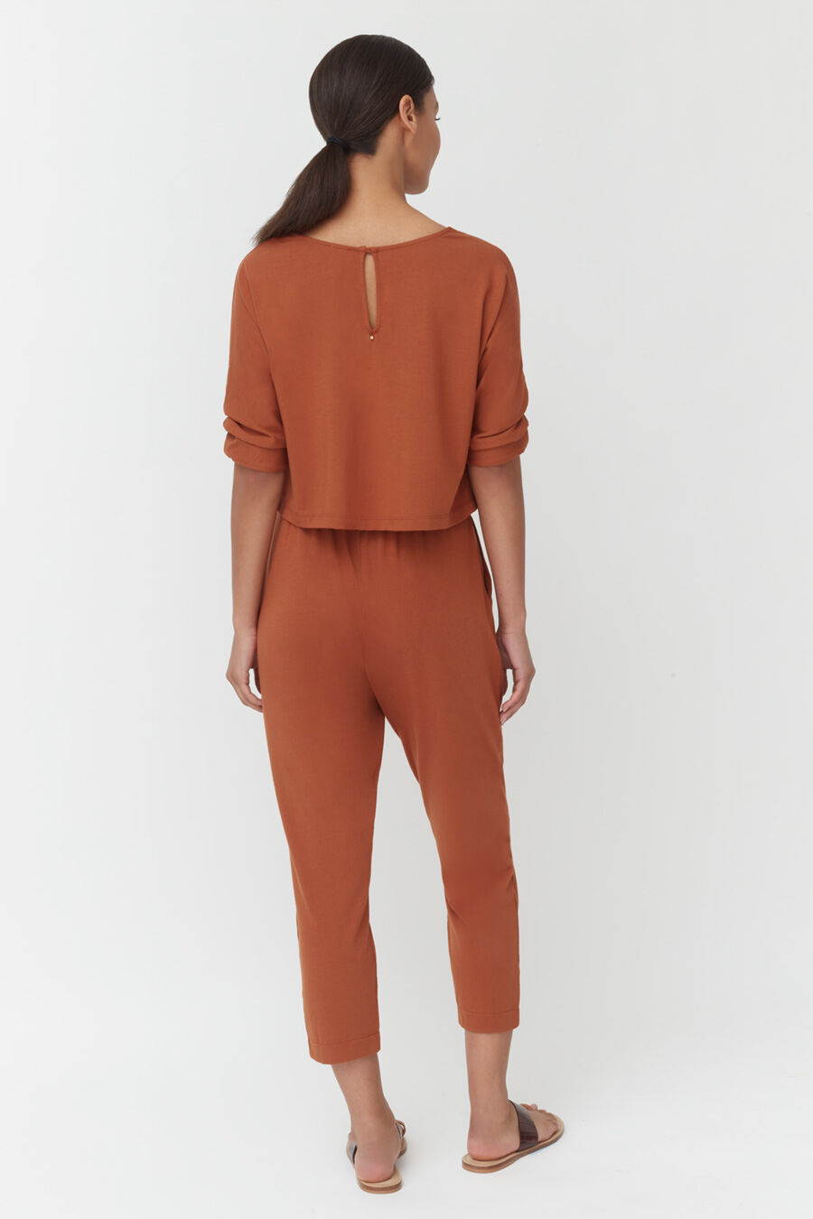 Woman seen from behind, wearing a jumpsuit with a small keyhole back detail.