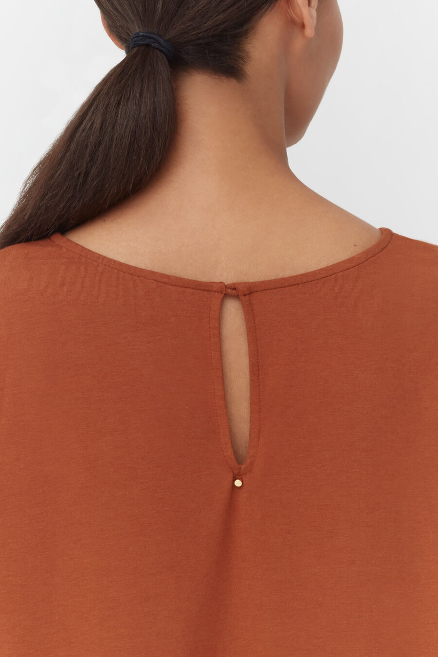 A woman from behind showing the top of her shirt with a button closure.