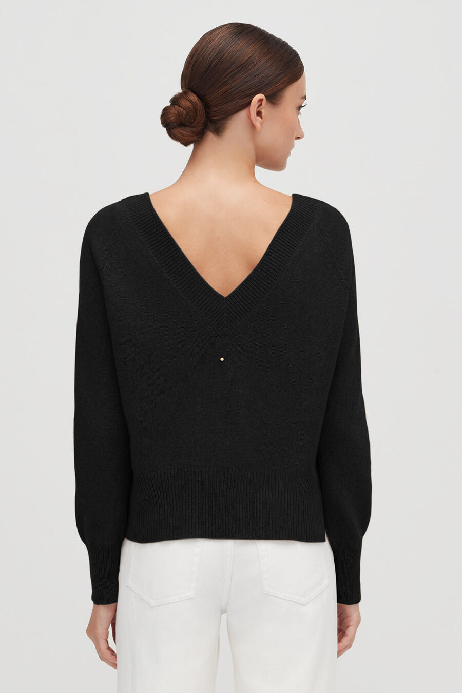 Woman in a v-neck sweater, viewed from the back.