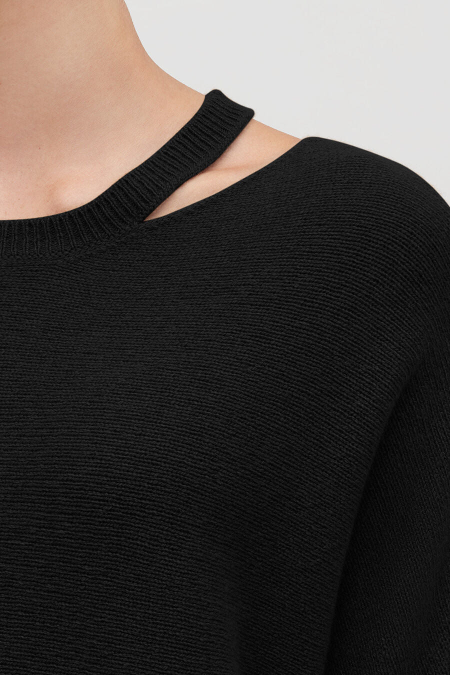 Person in sweater with shoulder cut-out detail.