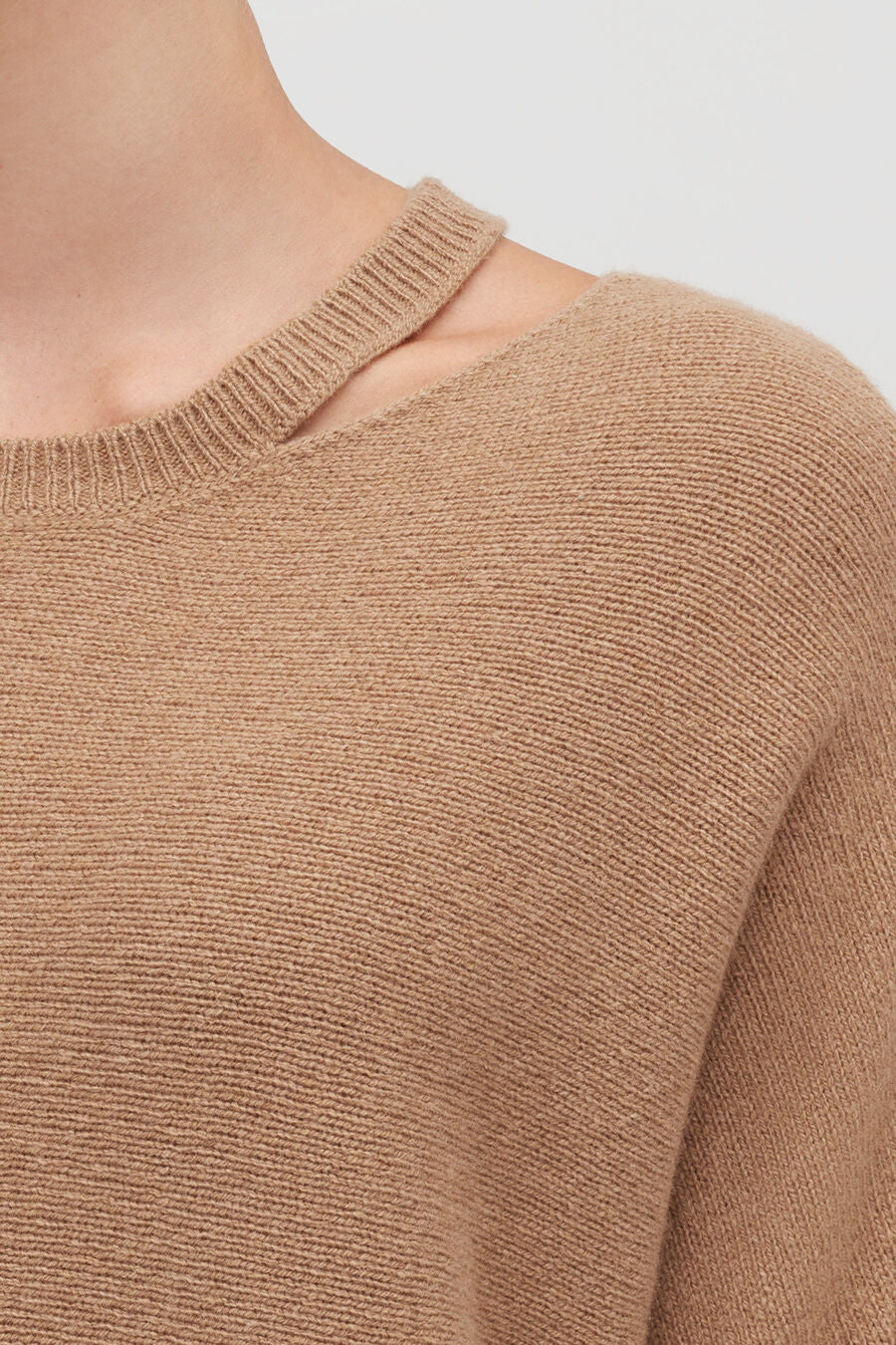 Close-up of a person wearing a sweater with a round neckline.