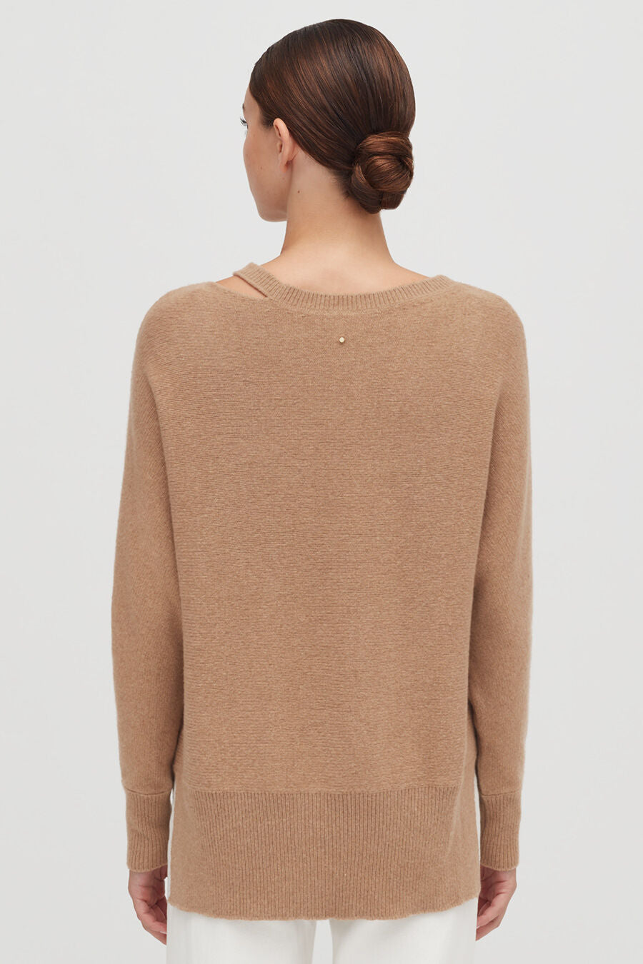 Woman seen from behind with a bun hairstyle wearing a sweater.