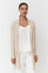 Woman standing in a cardigan and top with a neutral expression.