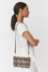 Woman standing sideways with a shoulder bag