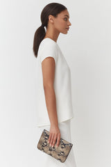 Side profile of a woman holding a clutch bag.