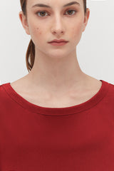 Woman in a crew neck top looking directly at the camera.