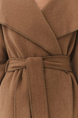 Close-up of a belted coat with overlapping front flaps.