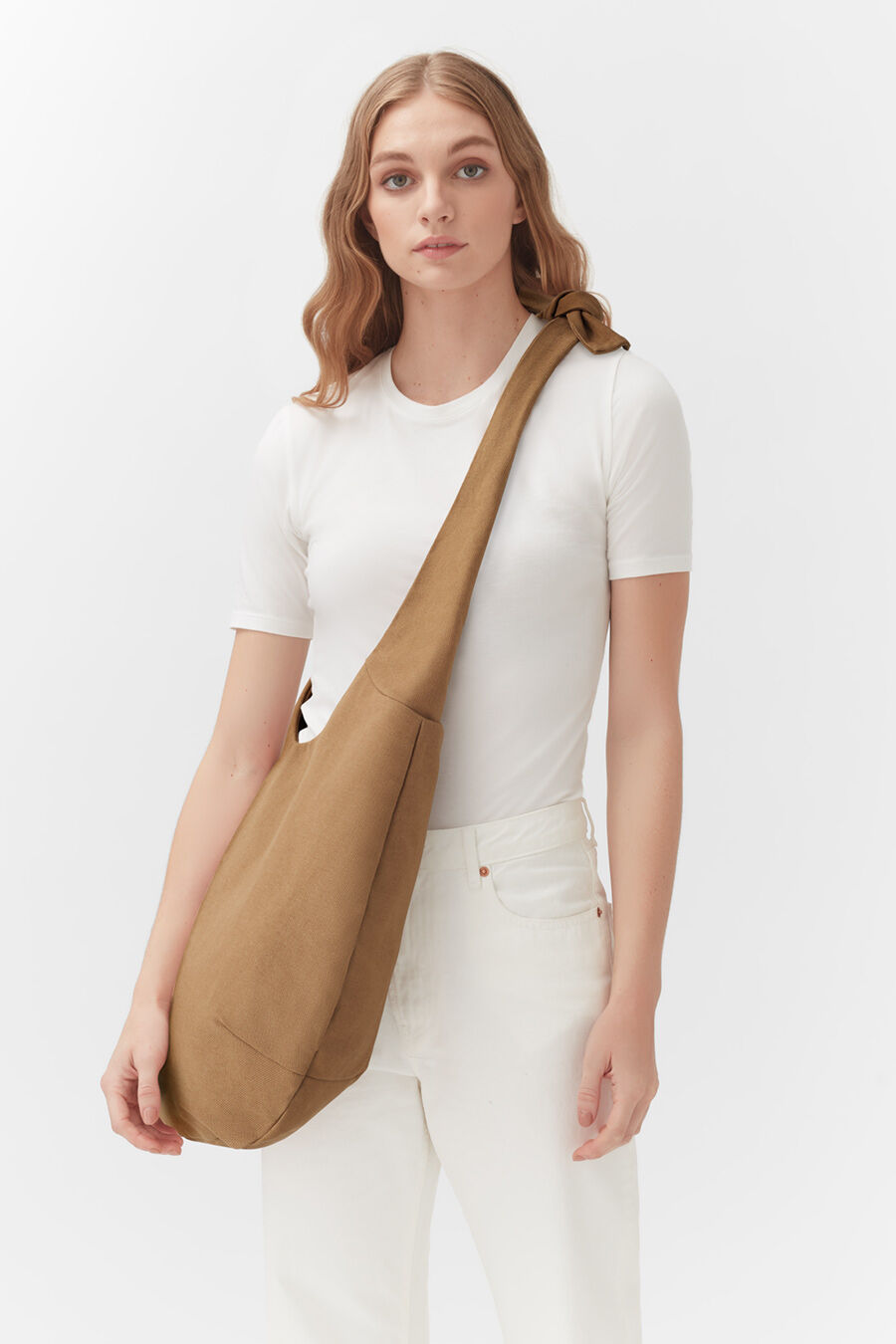 Woman standing with a shoulder bag.