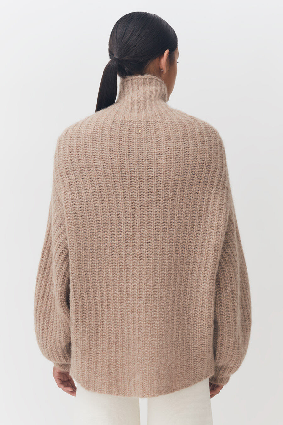 Woman in a sweater viewed from the back with hair in a ponytail.