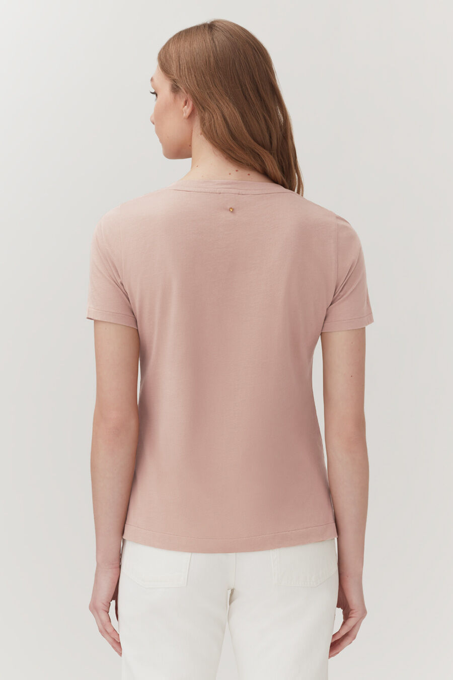 Woman seen from behind, wearing a short-sleeved top and pants, standing upright.
