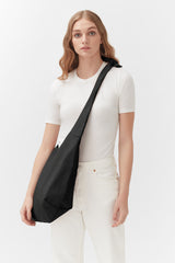 Woman standing with a shoulder bag.