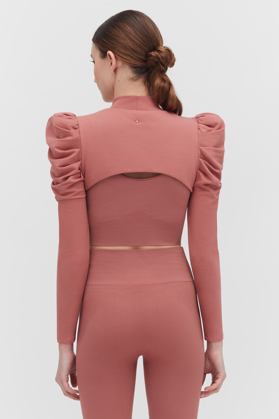 Woman seen from behind wearing a long-sleeve top with puffed shoulders.