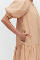 Person in a dress with a hand on waist, elbow bent.
