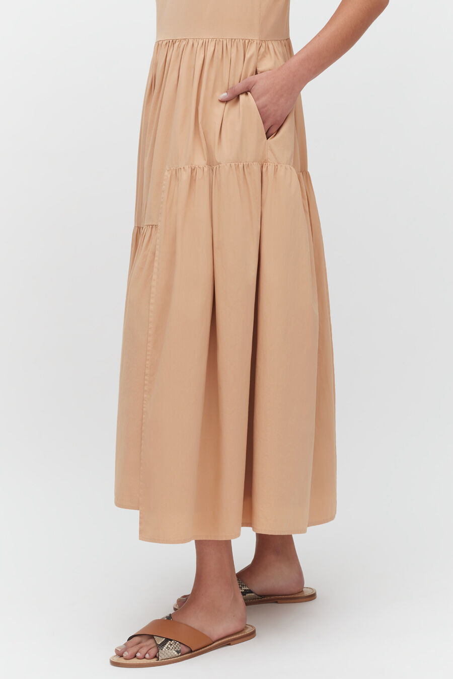 Person pointing to pocket on long skirt, wearing sandals.