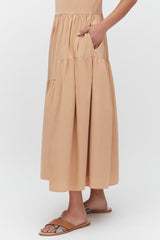 Person pointing to pocket on long skirt, wearing sandals.