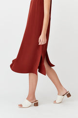 Person wearing a long dress and sandals walking.