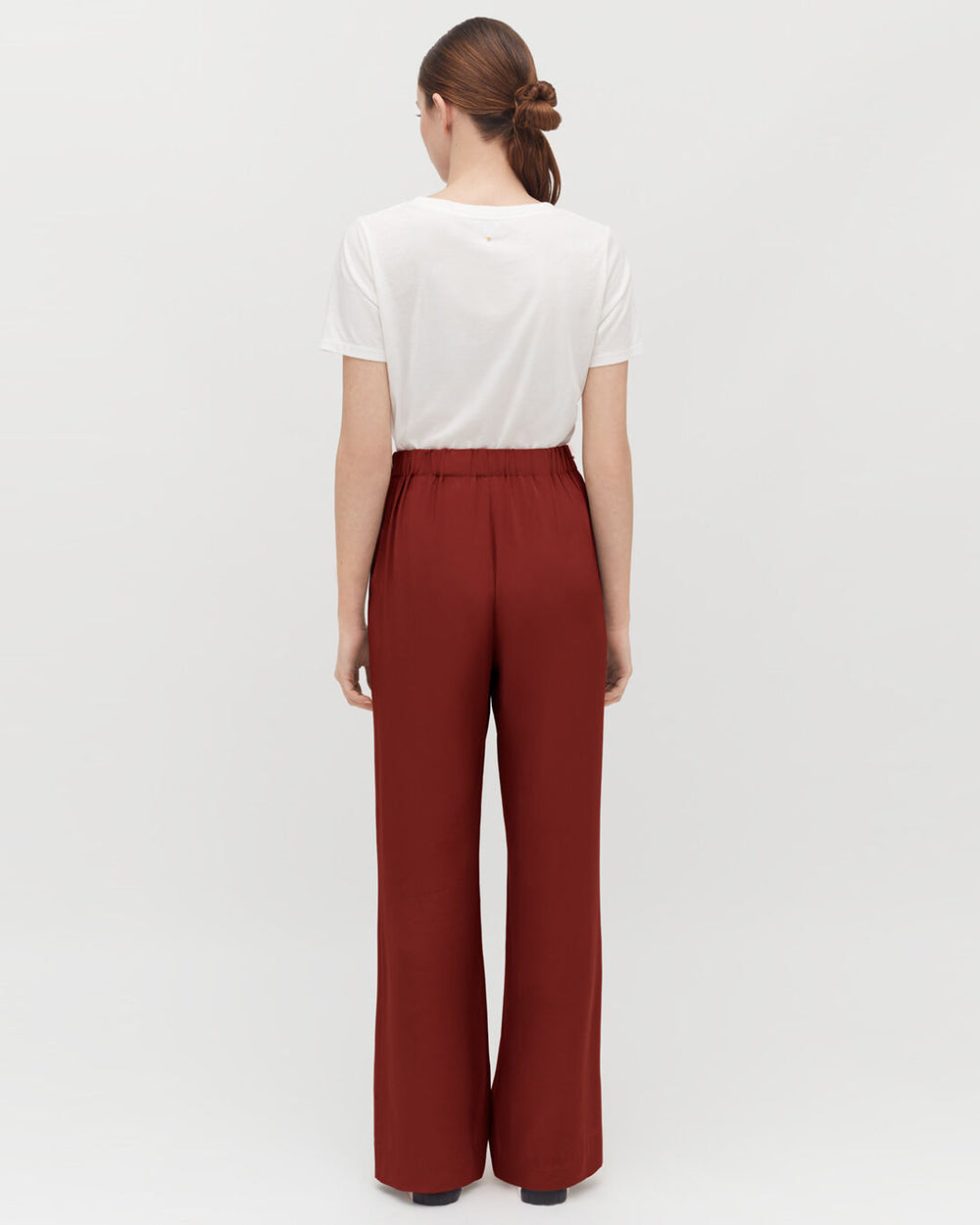 Woman standing with her back to the camera wearing pants and a T-shirt.